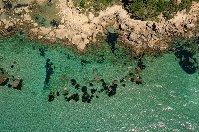 Turquoise shallow waters and rocks at Leventochori beach from above