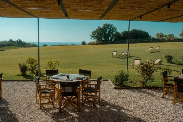 Outdoor dining table framed by the green lawn and the sea
