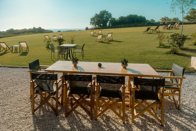 Long table on the terrace with deck chairs scattered on the lawn