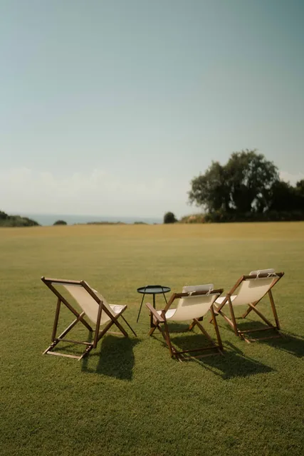 Three deck chairs on the lawn facing the sea