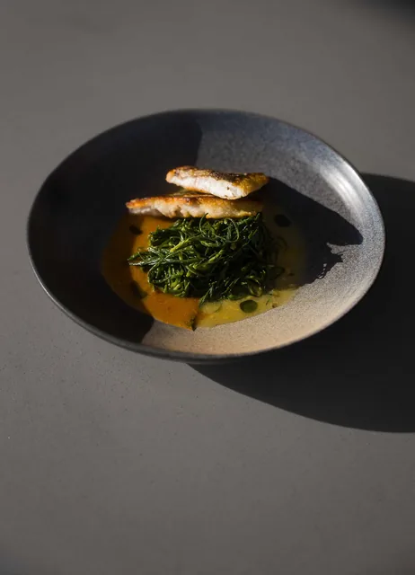 Fish fillet of the day with sauteed greens and bisque